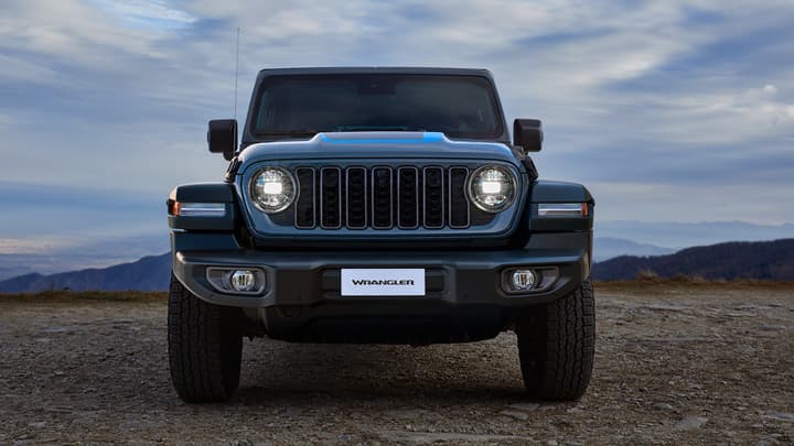 Front end shot of a blue Jeep Wrangler with a desert background