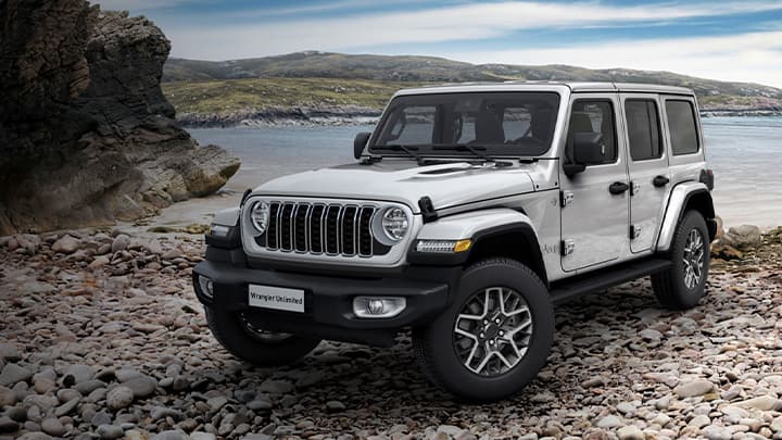 White Jeep Wrangler parked on some cobble stones with a lake in the background