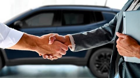 Close up of two men shaking hands, completing a car sale