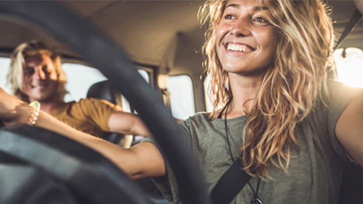 Close up of two young people sitting in the front seats of a Jeep