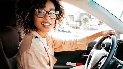 Young woman looking out the side window of a Jeep whilst sat in the driver's seat