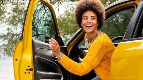 Young woman climbing into the driver's seat of a yellow Jeep Avenger