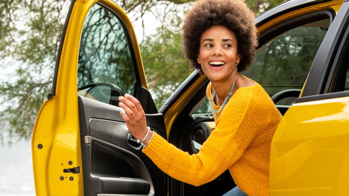 Young woman climbing into the driver's seat of a yellow Jeep Avenger