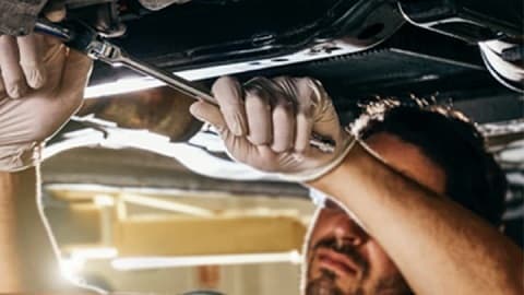 Technician servicing the underside of a Jeep
