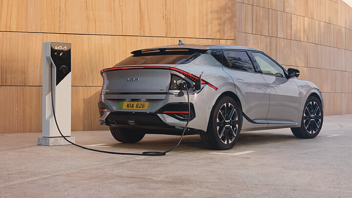 Silver Kia EV6 parked in front of a beige wall being charged