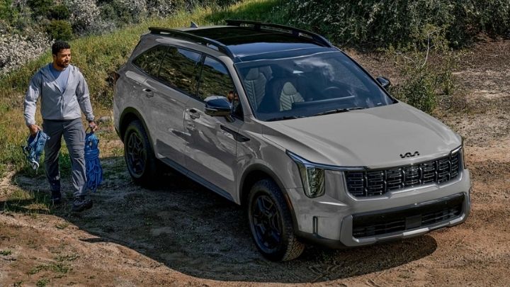 Silver Kia Sorento parked in the woods with a man walking beside it
