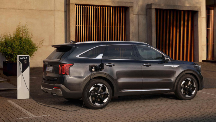 Black Kia Sorento Hybrid being charged at home in front large wooden doors