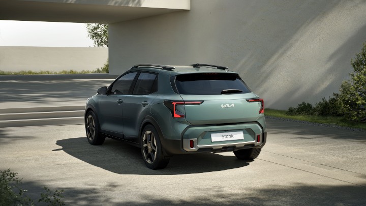 Green Kia Stonic compact SUV shown from a rear three‑quarter angle in a modern environment