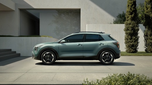 Green Kia Stonic compact SUV shown in full side profile on a contemporary driveway