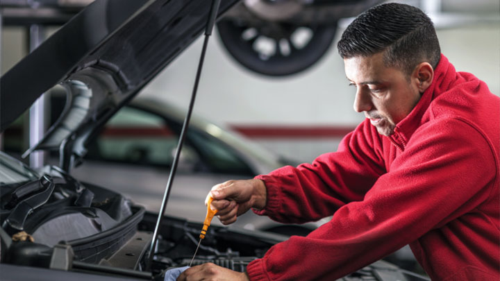 technician checking oil level on engine dipstick