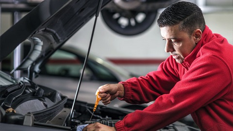 technician checking oil level on engine dipstick