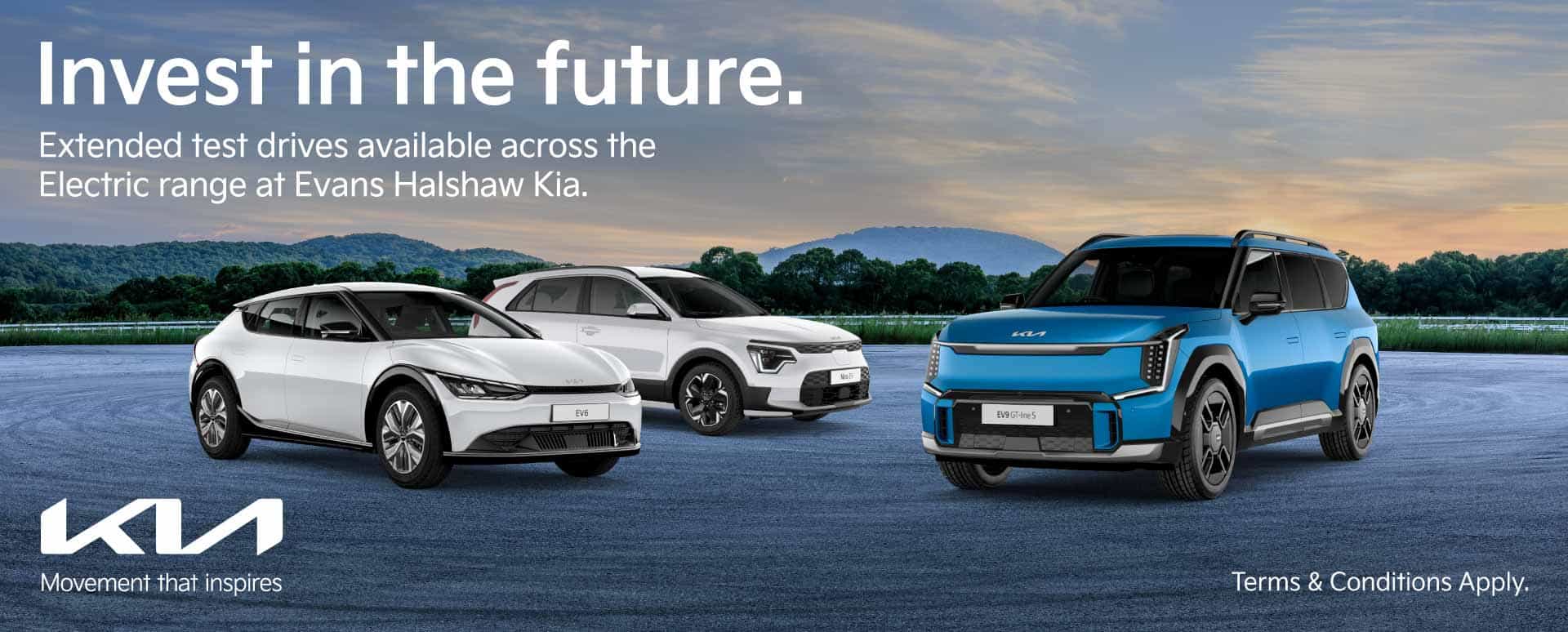 Two white EVs and one blue electric vehicle. Parked in a forest with a nice cloudy ski in the background