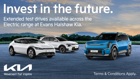 Two white EVs and one blue electric vehicle. Parked in a forest with a nice cloudy ski in the background