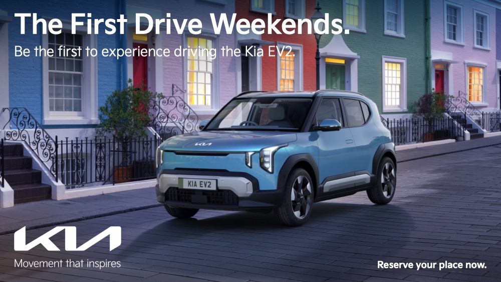 Blue Kia EV2 Driving Next To Terraced Houses
