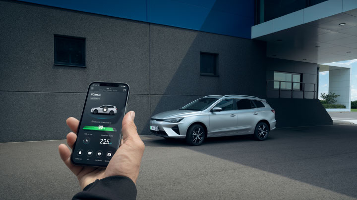 Man Holding Phone Infront of Silver MG5 EV Looking at Charging Statistics