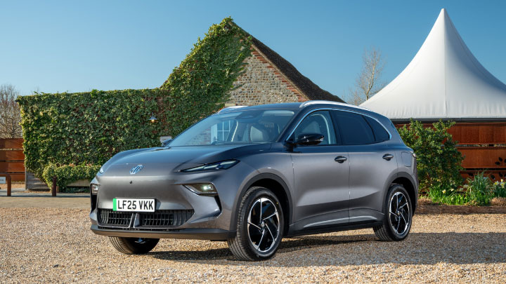 Silver MGS5 EV parked in front of a large country house