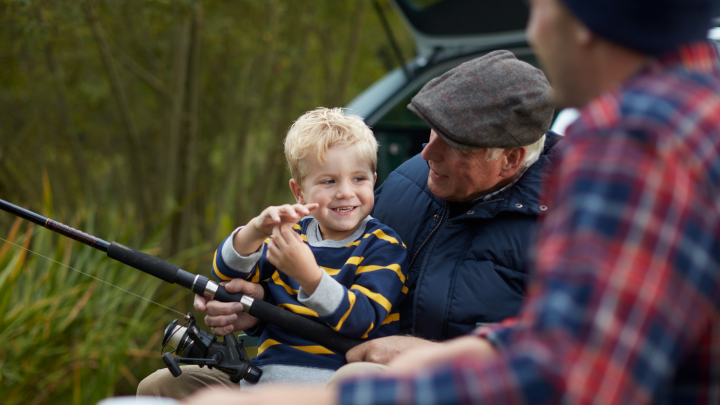 Elderly man with grandson, sitting behind a car doing some fishing