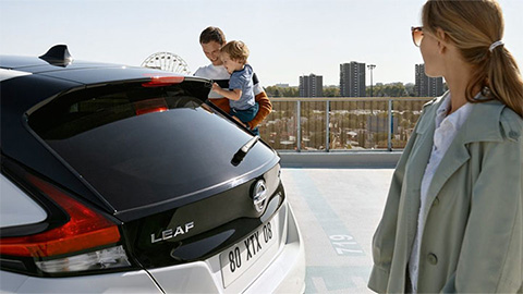 Young family standing next to a white Nissan LEAF