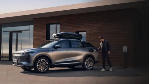 Man charging his OMODA 9 in front of a modern looking house