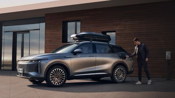 Man charging his OMODA 9 in front of a modern looking house