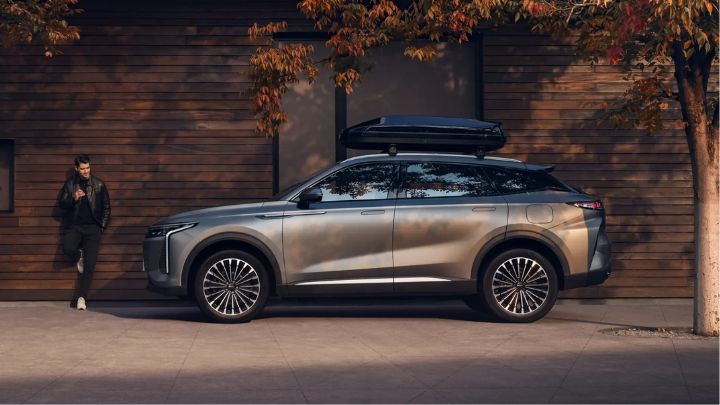 Silver OMODA 9 parked in front of a wooden walled house