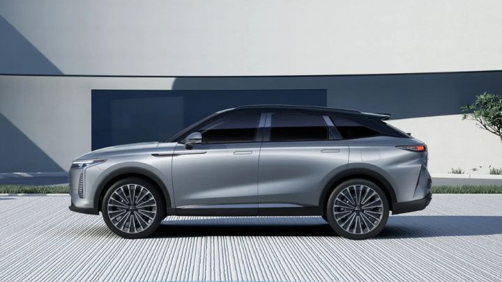 Side of the OMODA 9 that is parked in front of a futuristic looking house