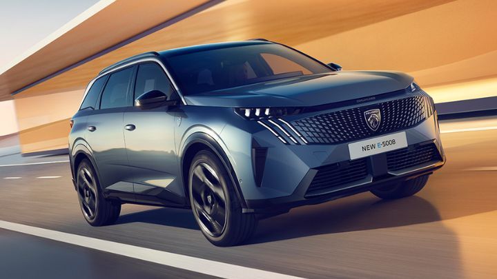 Grey Peugeot e-5008 driving in a modern looking road