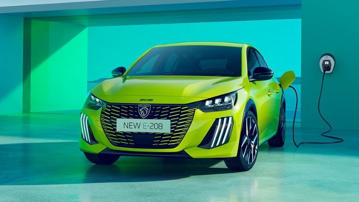 Yellow Peugeot e-208 being charged in front of a green wall