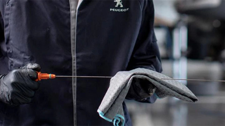 technician wiping oil off a vehicle dipstick