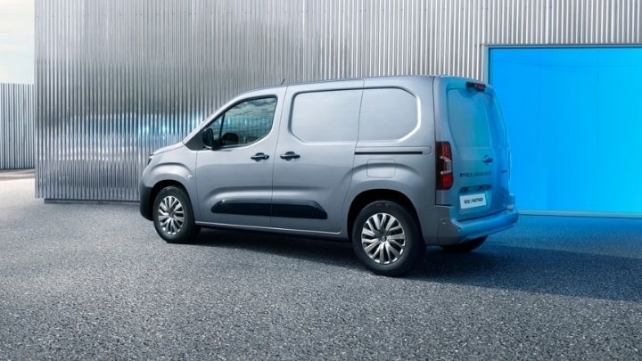 Side view of a silver Peugeot e-Partner parked in front of a grey wall