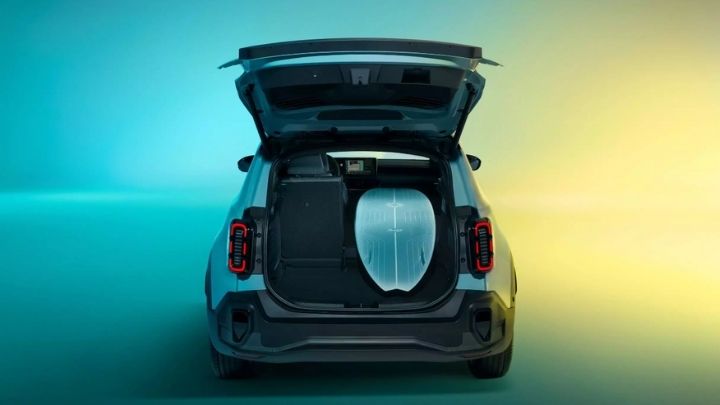 Open boot of the new Renault 4 showcasing a surfing board. The car is parked on a blue and yellow lit background.