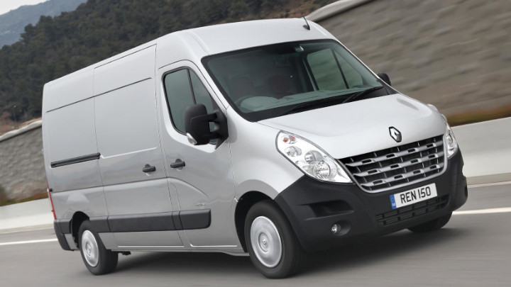 Front Exterior of a Silver Renault Master Van Driving Along a Road Lined by a Wall