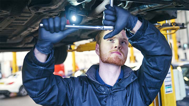 technician servicing underside of vehicle