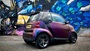 wrapped smart car in front of graffiti wall