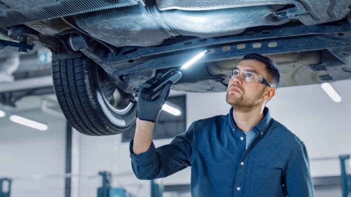 Technician checking the underside of a car