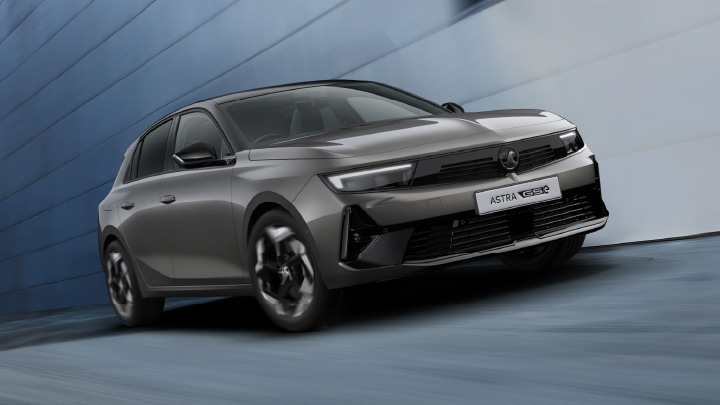 Grey Vauxhall Astra GSe driving in front of a blue wall