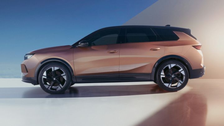 Side of Vauxhall Grandland facing the camera. The vehicle is being charged and the background is white and blue.