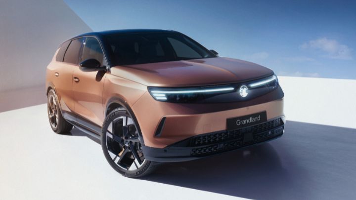 Face of Vauxhall Grandland facing the camera. The vehicle is being charged and the background is white and blue.