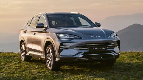 Silver BYD Seal U DM-i parked in the grass with mountains in the background