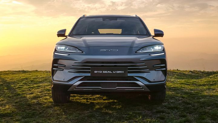 Front of a silver BYD Seal U DM-i parked in the grass with mountains in the background