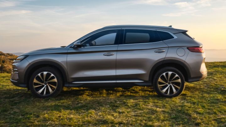 Side of a silver BYD Seal U DM-i parked in the grass with mountains in the background