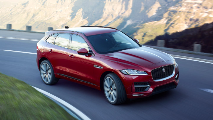 Red Jaguar F Pace driving on the road.